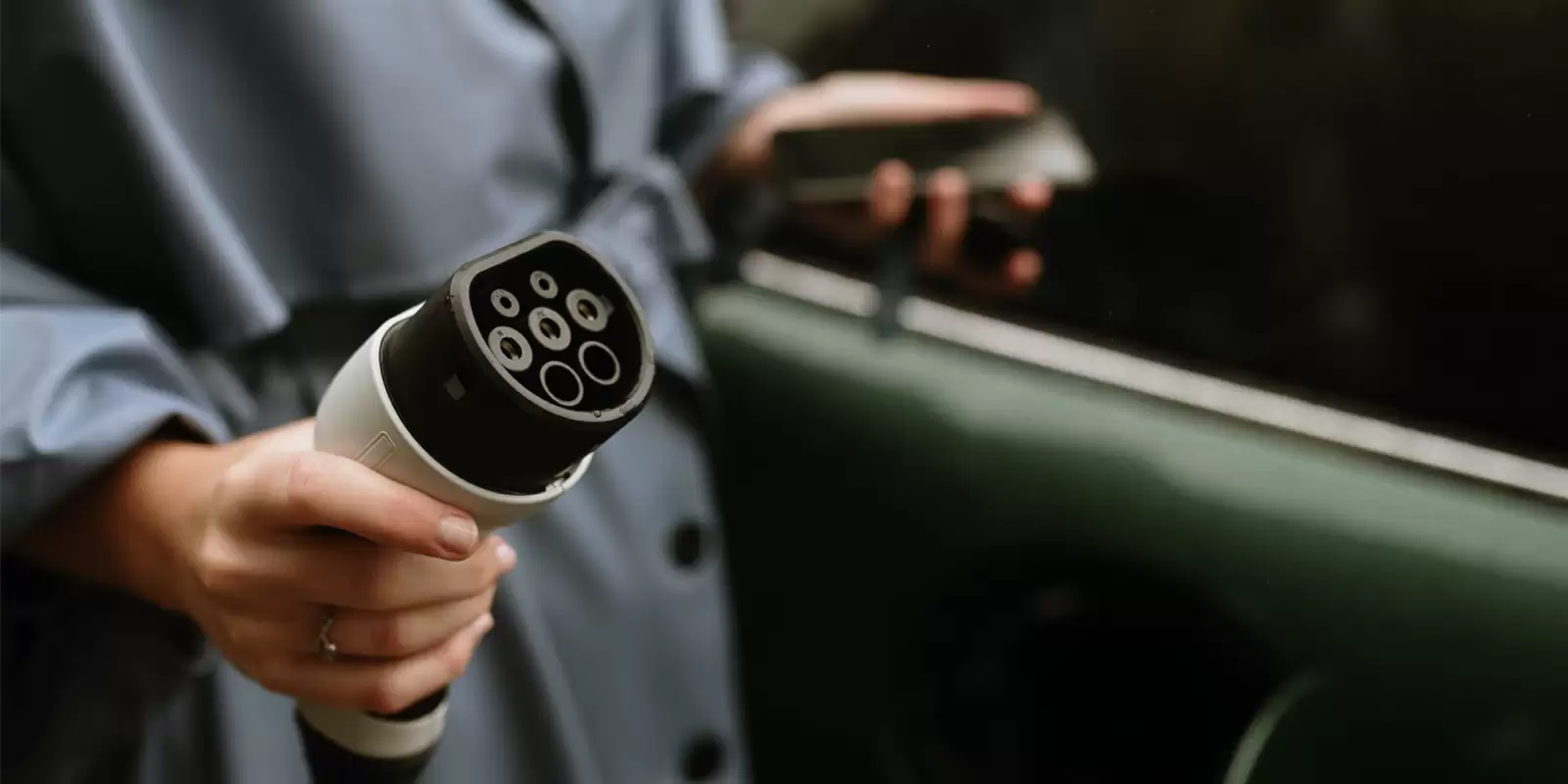 Detalle de una mano sosteniendo un conector para cargar un coche eléctrico